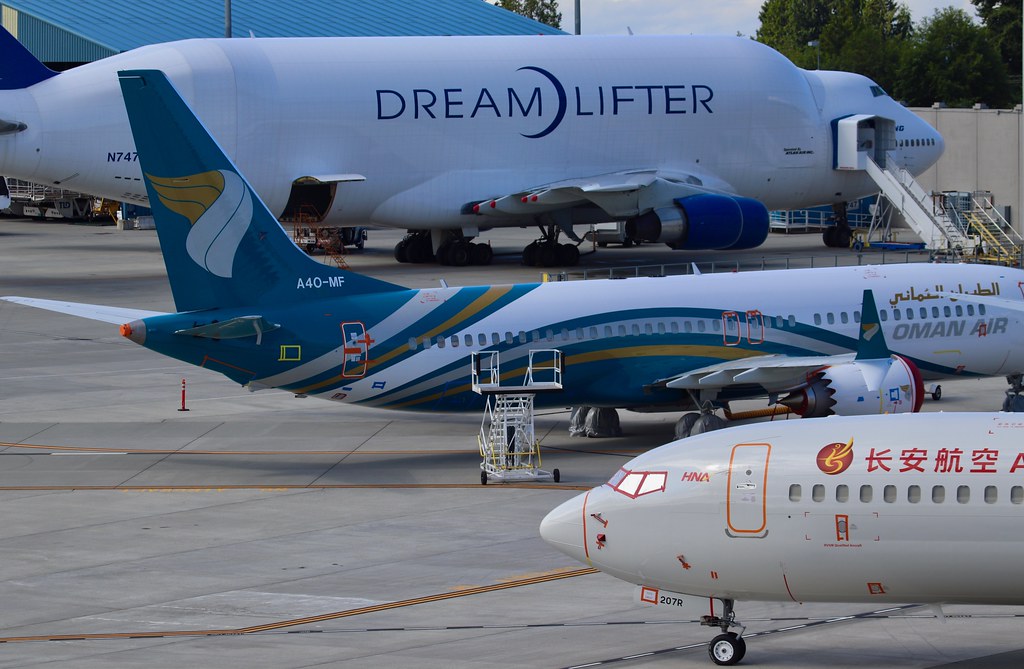 A white Boeing Dreamlifter cargo plane behind two 737 jets in airline paint on the ramp at Boeing's Everett factory