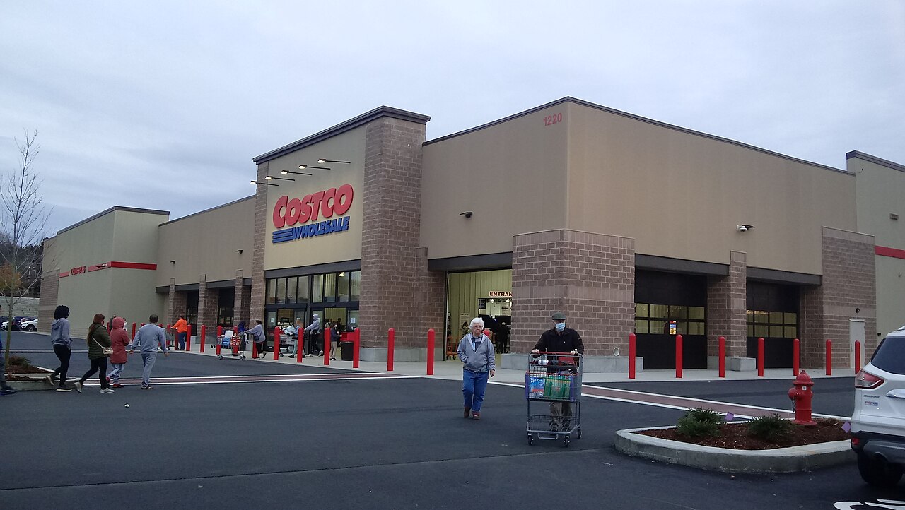 Shoppers with carts outside a Costco Wholesale warehouse, its red and blue sign above the entrance